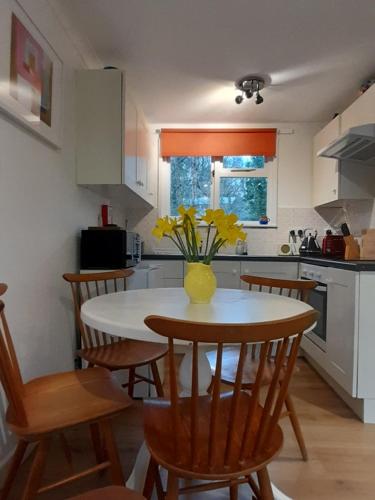 a kitchen with a table with a vase of flowers on it at Woodland Retreat in Uny Lelant
