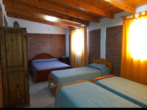 マラルグエにあるEl Pasaje 2のレンガの壁、ベッド3台が備わるベッドルーム1室