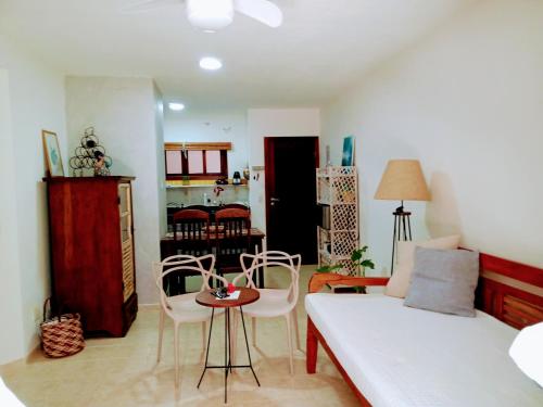 uma sala de estar com um sofá, uma mesa e cadeiras em Apartamento Hibiscus Condomínio Village Praia Imbassai em Imbassaí
