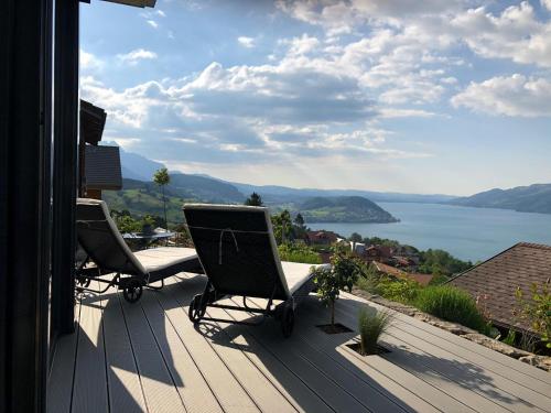 a balcony with two chairs and a view of a lake at Moderne Unterkunft mit Panoramablick auf Thunersee in Krattigen