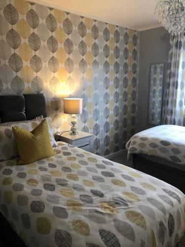a bedroom with two beds and a lamp on a wall at Skerrols in Broadford