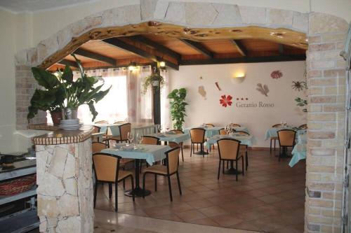 un ristorante con tavoli e sedie in una stanza di Hotel Geranio Rosso a Stintino