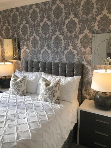 a bedroom with a white bed with pillows and a wall at Skerrols in Broadford