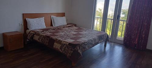 a bedroom with a bed and a large window at Kumaragiri Cottages Kodaikanal in Kodaikānāl