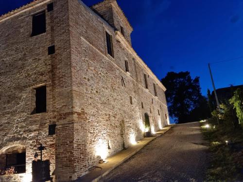 a large brick building with lights on the side at Castello di Petecciano B&B in Mosciano SantʼAngelo
