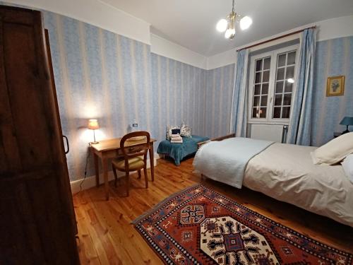 a bedroom with a bed and a desk and a table at La Grange de Lily in Vic-sur-Cère