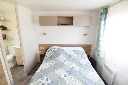 a small bedroom with a bed and a window at Mobil Home 8 personnes in Les Mathes