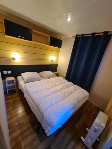a large bed in a room with a blue curtain at L'indépendant in Saint-Chéron