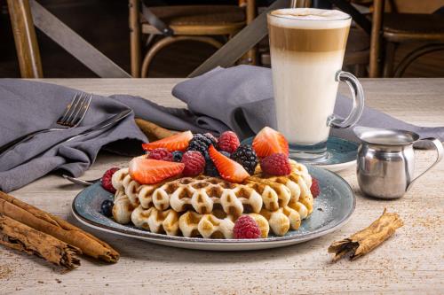 a waffle cake with fruit on a table with a drink at TRYP by Wyndham San Luis Potosi Hotel & Suites in San Luis Potosí