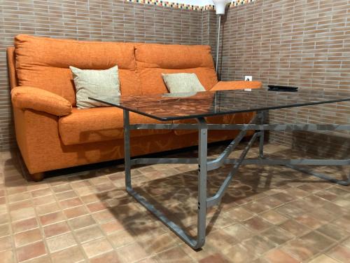 un sofá naranja y una mesa de cristal frente a un sofá en Tranquilo espacio con entrada independiente, en Sevilla