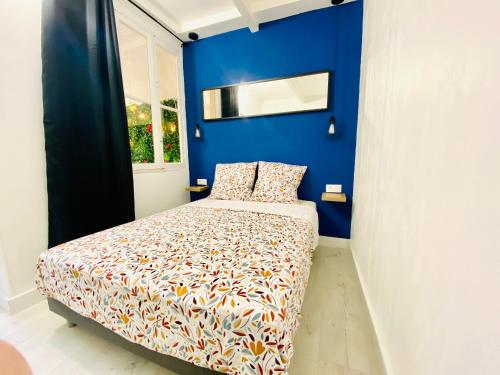 une chambre avec un lit avec un mur bleu dans l'établissement SPLENDIDE T2 NEUF COOCOONIG AVEC PETIT PATiO, à Sète