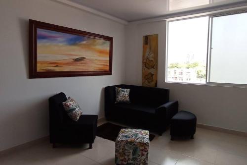 a living room with two chairs and a painting on the wall at Edificio Tony - Alojamiento Aparta-Hotel in Barrancabermeja