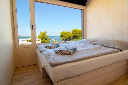 a bed in a room with a large window at MODERN BEACH VILLAS - Buqez Camp resort in Drage