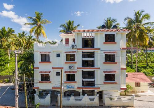 a white building with palm trees in the background at Hotel Turístico Marian in Las Terrenas