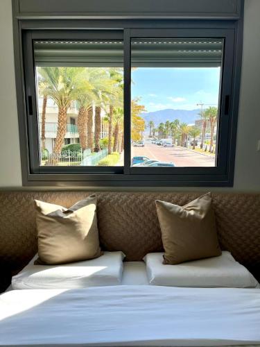 a window above a bed with a view of a street at Esterin Royal Park Apartments Eilat in Eilat