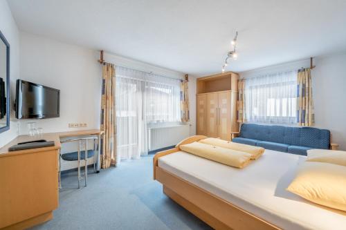 een slaapkamer met een groot bed en een blauwe bank bij Seehüter's Hotel Seerose in Oetz