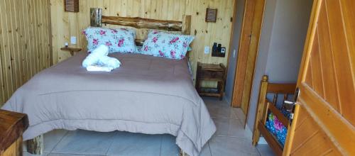a bedroom with a bed with a teddy bear on it at Chalés Manacá da Serra in Urubici