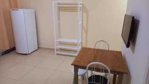 a kitchen with a wooden table and a refrigerator at Atlantica Suites in Guarujá