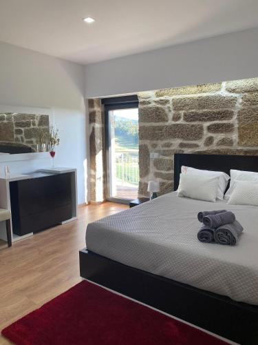 a bedroom with a large bed with a stone wall at Casa da Carreira in Mondim de Basto
