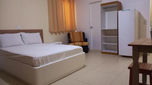 a bedroom with a white bed and a chair at Atlantica Suites in Guarujá