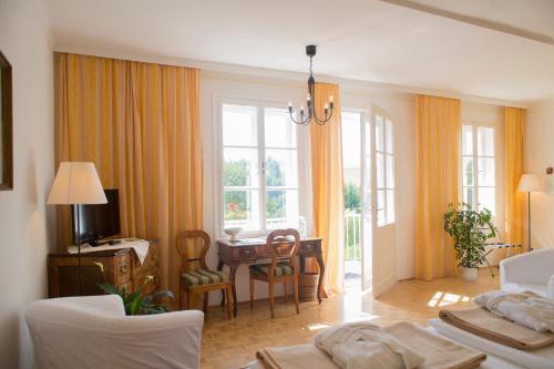 salon z żółtymi zasłonami, stołem i krzesłami w obiekcie Hotel Landsitz Pichlschloss w mieście Neumarkt in Steiermark