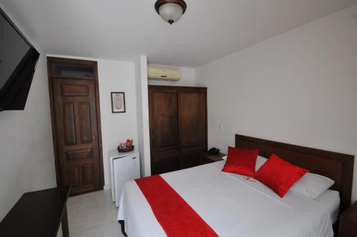 a bedroom with a bed with red pillows on it at Hotel San Julian in Buga