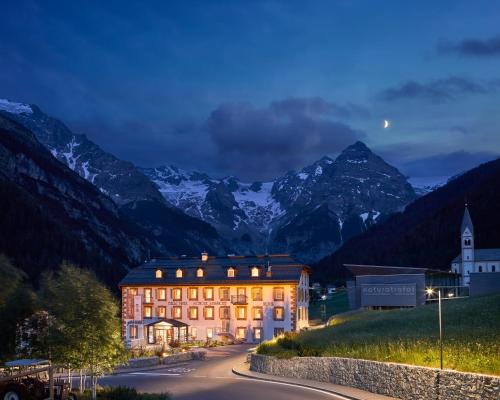 a building on a street with mountains in the background at Hotel Bella Vista in Trafoi