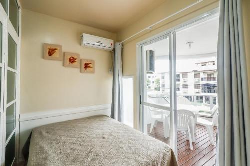 1 dormitorio con 1 cama y balcón con mesa en Apto a 30m do mar e wi-fi para 6 pessoas - HB33F, en Florianópolis