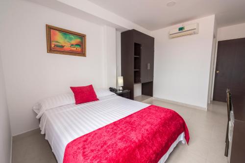 a bedroom with a white bed with a red blanket at Casablanca Hotel, RestoBar, Catering, Eventos & Turismo en Garzón in Garzón