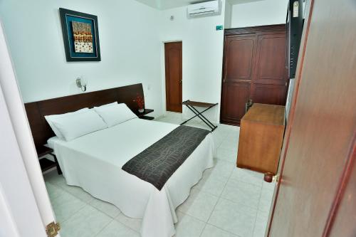 a bedroom with a white bed and a wooden door at Casablanca Hotel, RestoBar, Catering, Eventos & Turismo en Garzón in Garzón
