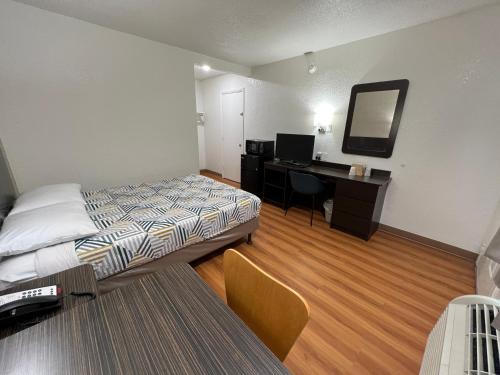 a hotel room with a bed and a desk with a mirror at Motel 6-Longview, TX in Longview