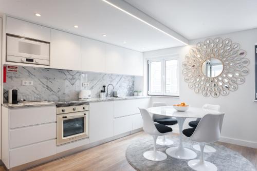 a white kitchen with a table and chairs at Embaixador Apartments&Suites in Lisbon