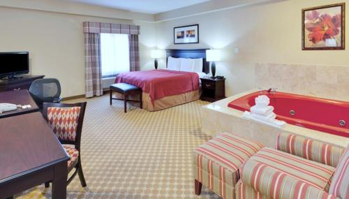 ein Hotelzimmer mit einem Bett und einer roten Badewanne in der Unterkunft Country Suites Absecon-Atlantic City, NJ in Galloway