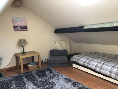 a bedroom with a bed and a chair and a lamp at Mena Cottage, Cosy Country and Quaint. in Hunmanby