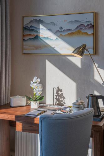 a desk with a blue chair and a desk lamp at Willis Hotel Business & Wellness in Zalaegerszeg