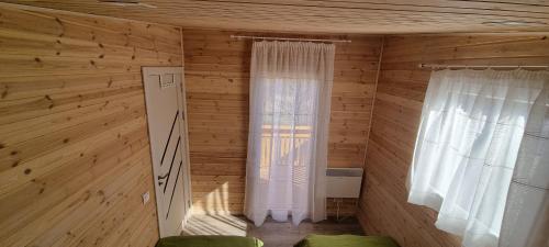 a small room with wooden walls and two windows at Căsuța de la luncă in Cireşu