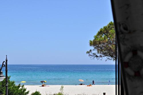 a beach with umbrellas and people on the beach at Stella Marina Budoni in Budoni