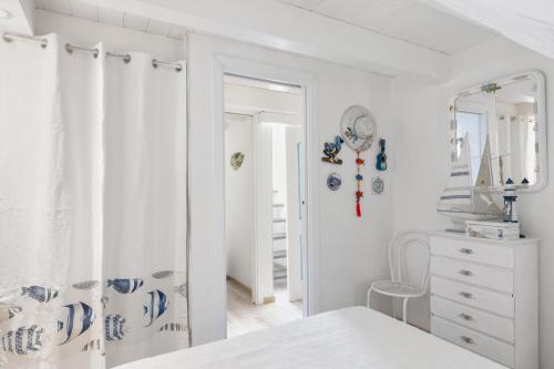Un dormitorio blanco con una cama y un espejo. en Giglio apartment vista mare e parcheggio privato, en Porto Rotondo