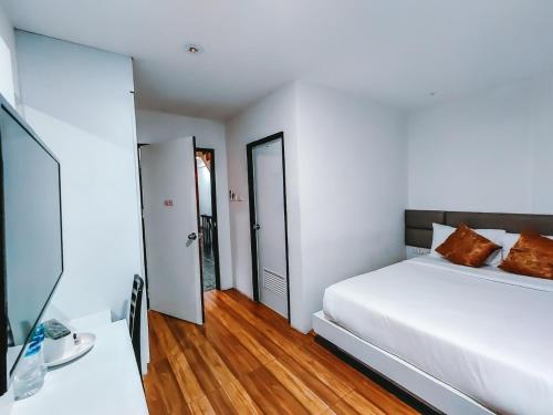 a white bedroom with a white bed and wooden floors at The Harbour Front Hotel in Suratthani