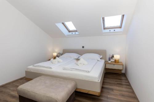 a bedroom with a white bed and two windows at Deluxe Apartment Stunning view in Jadranovo