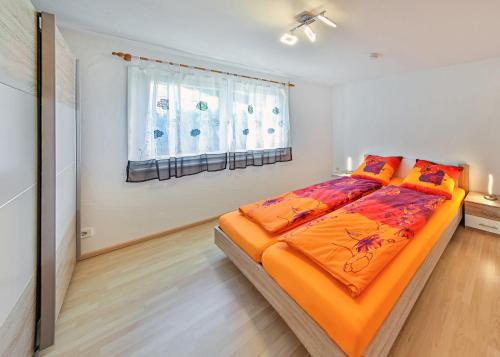 a bedroom with a bed with an orange comforter and a window at Firstberg Perle in Triberg