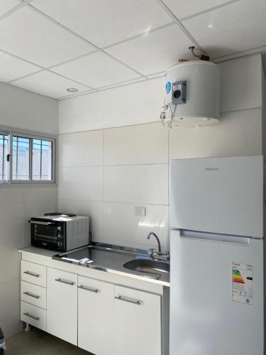 eine weiße Küche mit einer Spüle und einem Kühlschrank in der Unterkunft Departamento en La Punta in La Punta