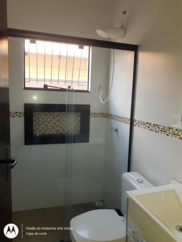 een badkamer met een douche, een toilet en een raam bij Casa de Praia em Barra Velha Itajuba SC por Temporada in Barra Velha