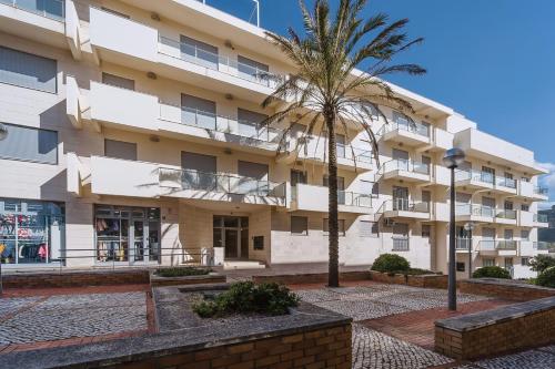 a building with a palm tree in front of it at Refúgio Villa Mar in Nazaré