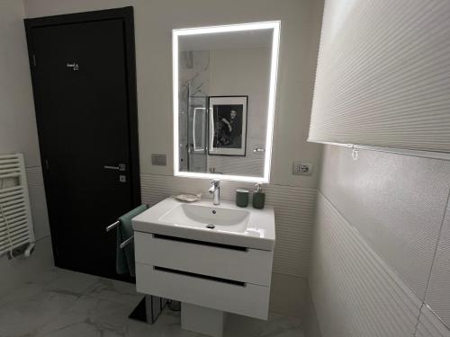 a white bathroom with a sink and a mirror at PAGANINI suits and apartments in Sirmione