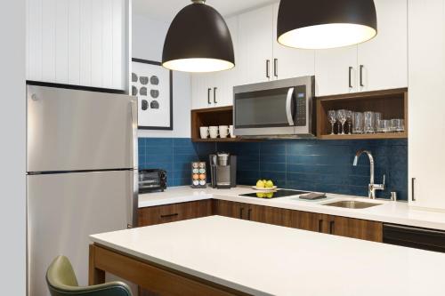 a kitchen with a white refrigerator and a sink at Staybridge Suites Rochester - Mayo Clinic Area by IHG in Rochester
