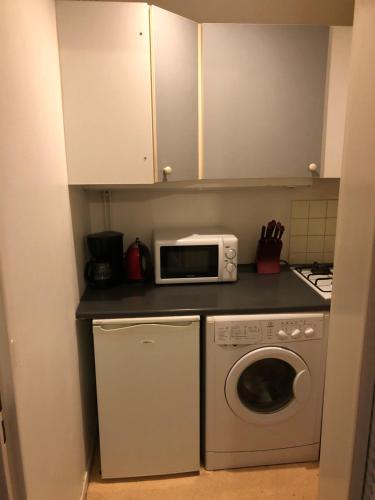 a kitchen with a washing machine and a microwave at Studio lumineux et confortable in Chaumont