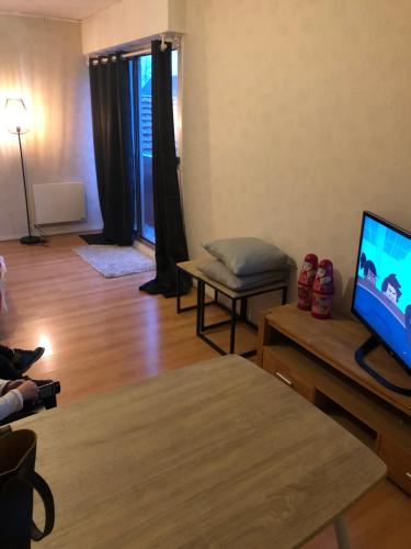 un soggiorno con TV a schermo piatto e tavolo di Studio lumineux et confortable a Chaumont
