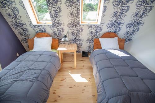 two beds in a room with blue and white wallpaper at Allika Holiday House in Pärnu