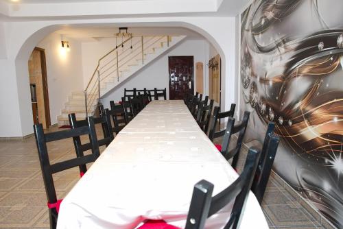 a long table with chairs in a room with a wall at Pensiunea Royal in Ranca